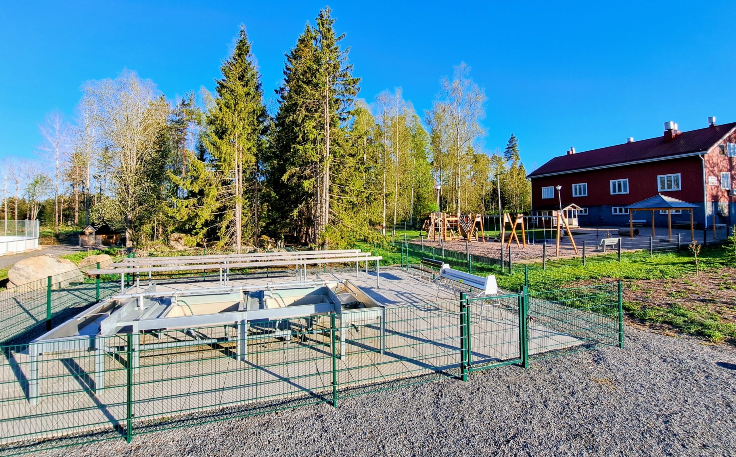 Matonpesupaikka kuivalla maalla, Taustalla metsää, päiväkotirakennus ja leikkipiha.