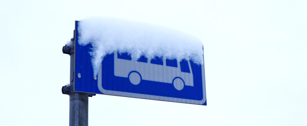 Bussipysäkin merkki, jossa on lunta päällä.