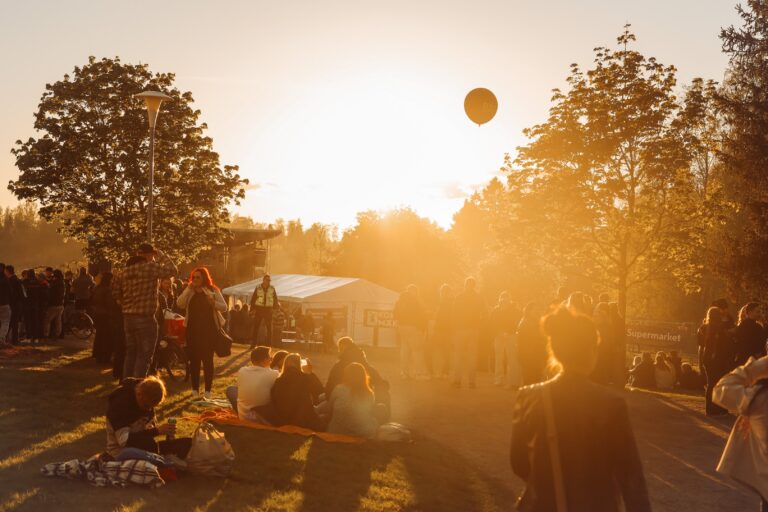 Auringonlasku kuva tapahtumasta, missä iso pallo leijailee taivaalla ja edessä on paljon ihmisiä.
