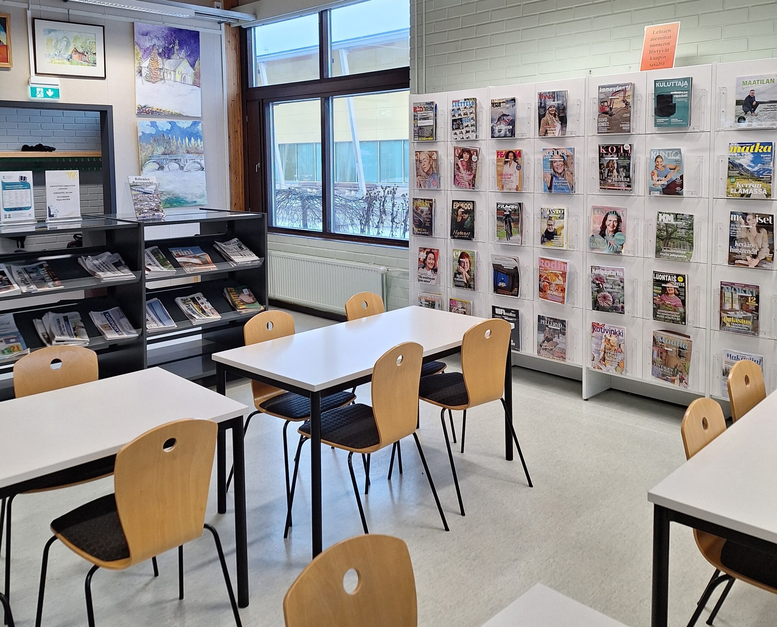 Pääkirjaston lukusali. Edustalla pöytiä ja tuoleja, taustalla lehtihyllyjä ja ikkuna.