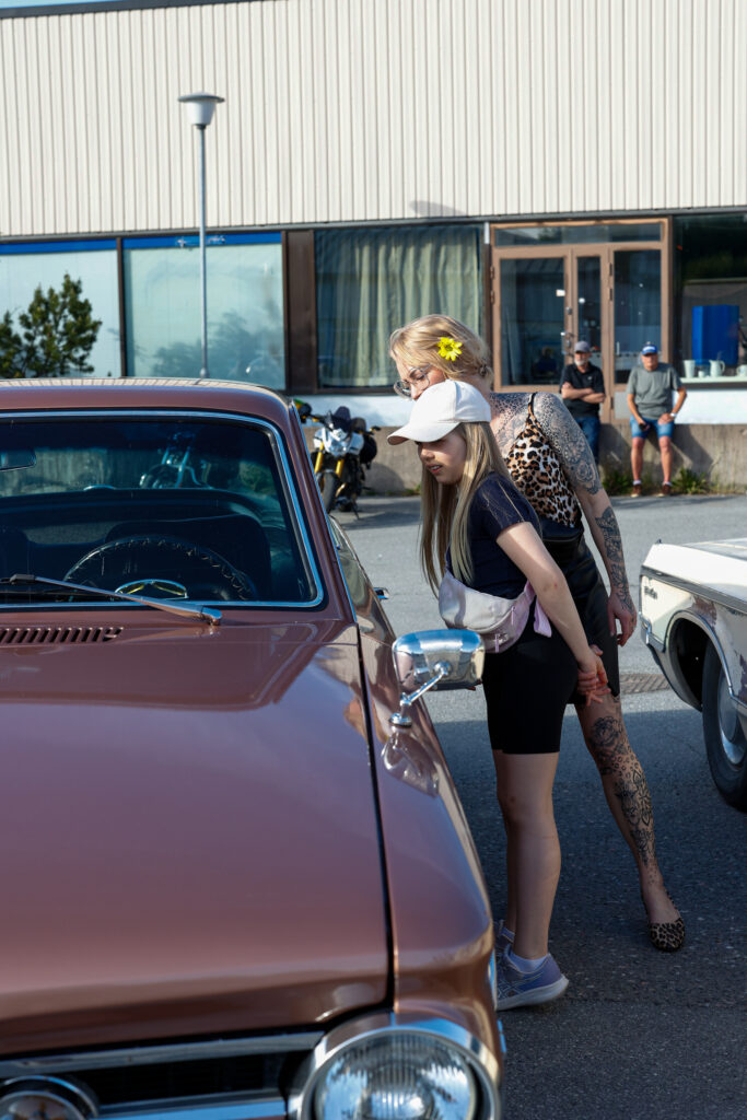äiti ja tytär ihailevat cruising-autoa.