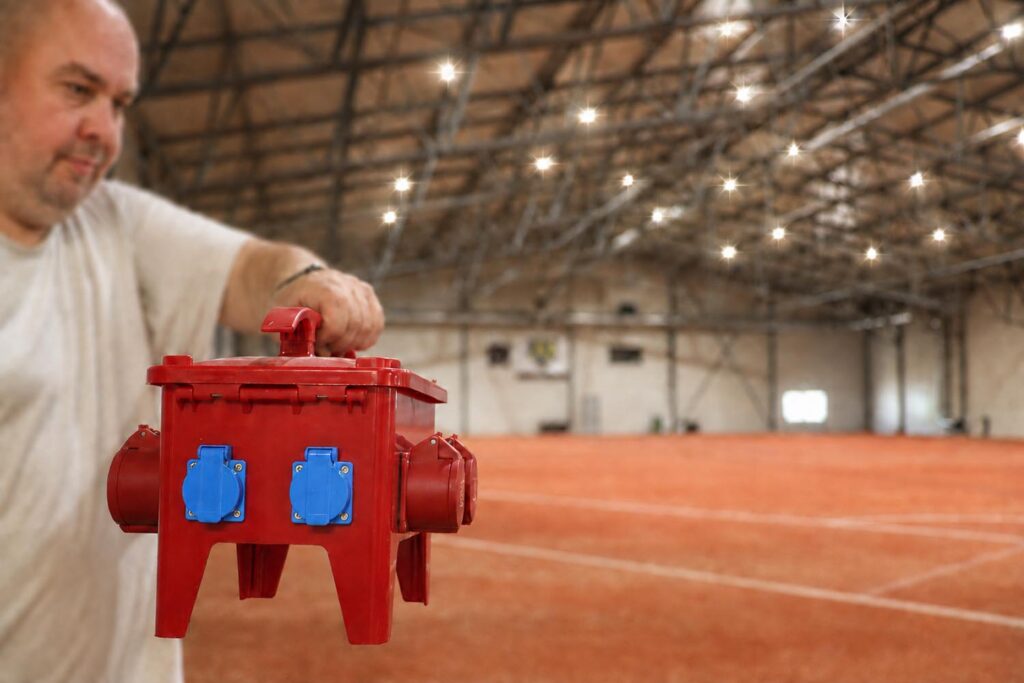 Mies pitää sähkökeskusta kädessään isossa hallissa.