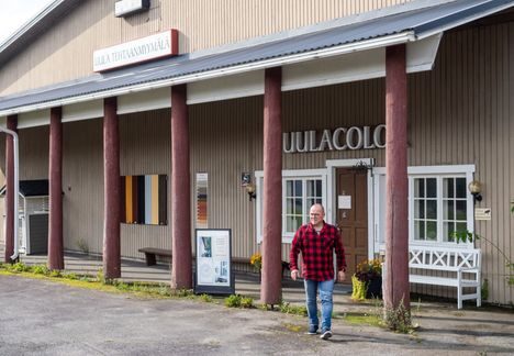 Kuva greigen talon edustalta, jossa mies seisoo pylväiden välissä.